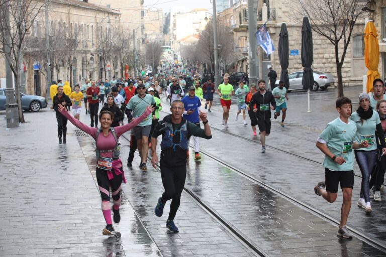 Runners smiling to camera as they take part in the Jerusalem Marathon 2024