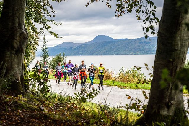 Runners in the foreground as they pass by Loch Ness during the Loch Ness Marathon 2024