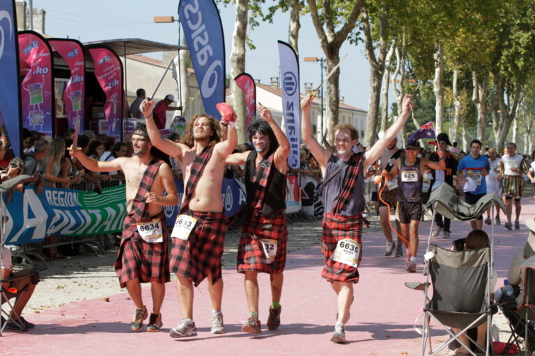 Runners in fancy dress approach the finish line at the Marathon du Medoc 2024