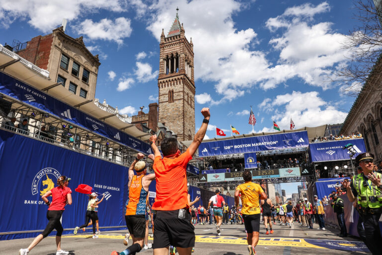 A runner celebrates as they cross the finish line of the Boston Marathon