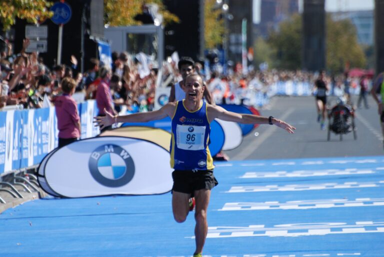 A Marathon runner celebrates crossing the finish line at the Berlin Marathon