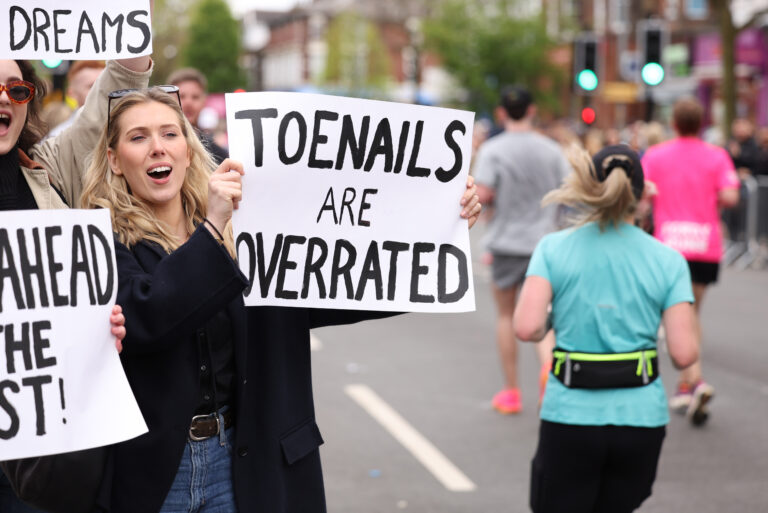 A spectator holds up a humorous sign during the Manchester Marathon 2025