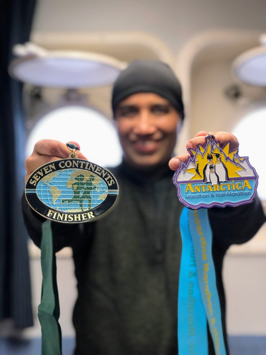 A Seven Continents Club finisher holds up his medals