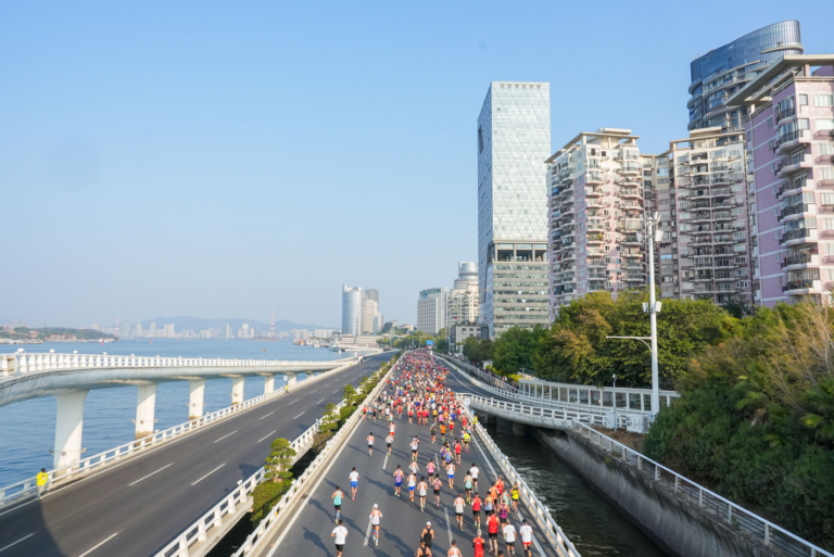 Runners passing along the shoreline at the Xiamen Marathon 2025