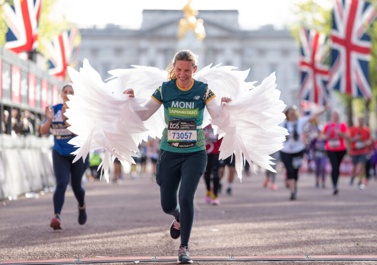 A runner in fancy dress crosses the finish line of the 2025 London Marathon