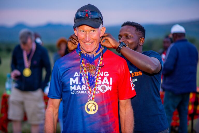 A runner is handed their medal having completed the Amazing Maasai Marathon