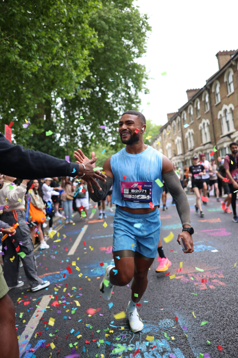 A runner high fives supporters during the Hackney Half Marathon