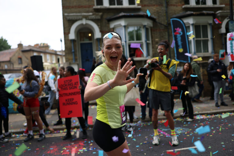 A runner runs through confetti during a boisterous Hackney Half Marathon
