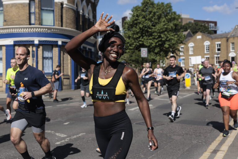 A runner waves to the camera during the Hackney Half Marathon