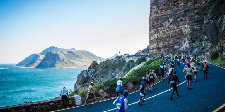 Runners passing by the ocean on a cliffside during the Two Oceans Ultra Marathon