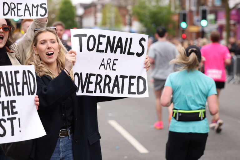 A spectator holds up a humorous sign during the Manchester Marathon 2026