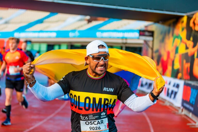 A runner holds the Colombia flag aloft at the finish of the TCS Amsterdam Marathon