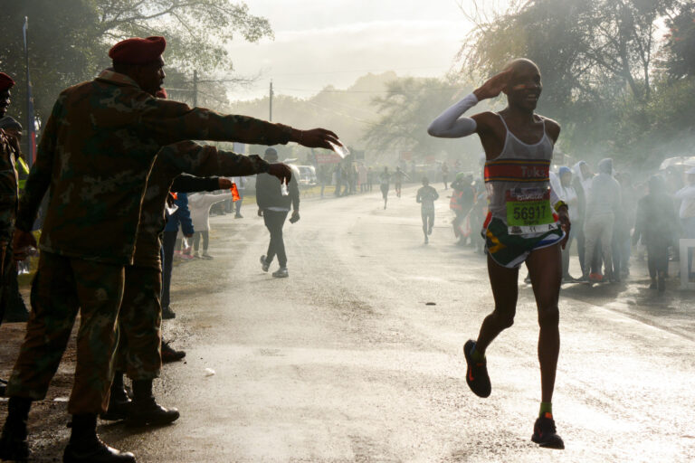 Picture of a runner passing a water stand at the Comrades Marathon