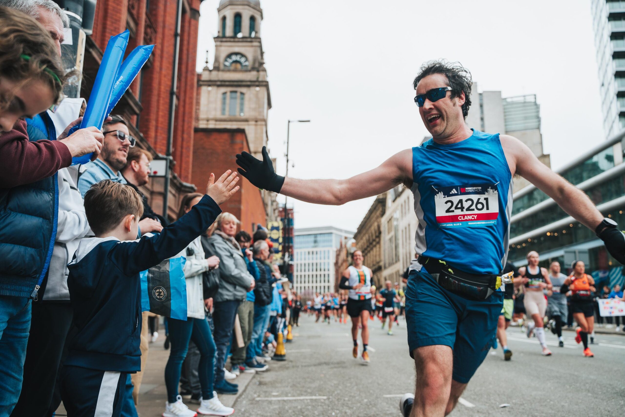 A runner interacting with supporters during the Manchester Marathon 2025